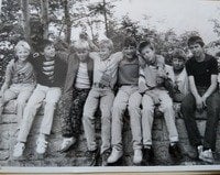 schwarz/weiß Foto, acht fröhliche Jungen sitzen auf einer Mauer