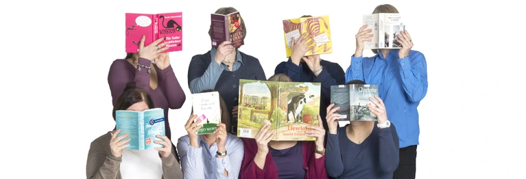 8 Mitarbeiter der Hiltruper Buchhandlung, die sich ein Buch vor das Gesicht halten