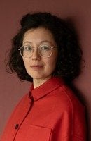 Autorinnenfoto Yuko Kuhn. Schwarze Haare, Brille, rote Bluse, freundlich lächelnd