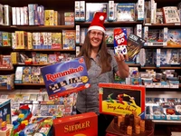 Gerlinde Droste präsentiert Gesellschaftsspiele vor dem Spieleregal