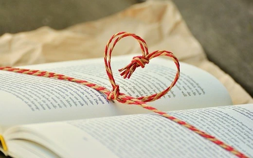 Ein aufgeschlagenes Buch mit einem Herzen aus Geschenkband