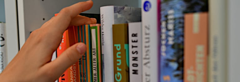 Eine Hand greift nach Büchern