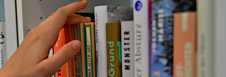 Eine Hand greift nach Büchern