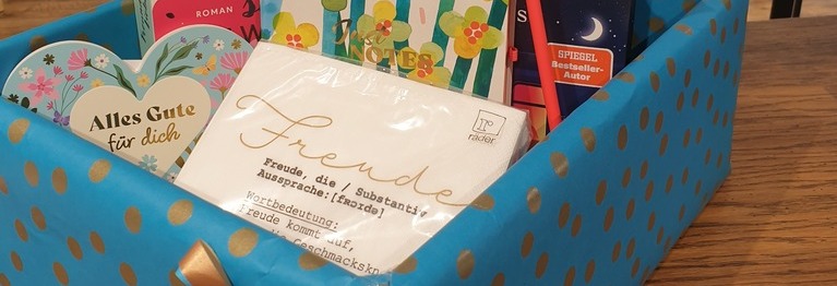 Geschenkbox mit Karten und Büchern vor Bücherregal